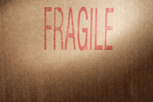 Closeup of a brown cardboard box with word "Fragile" stamped with red ink.