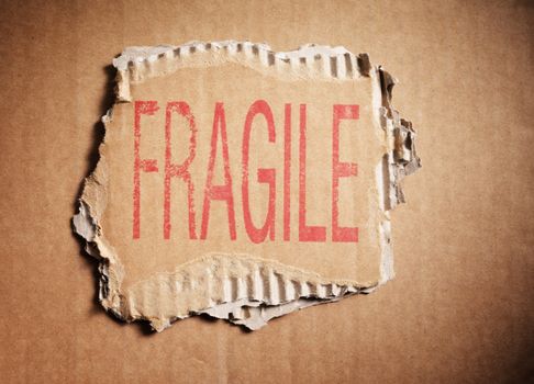 Word Fragile stamped on a piece of brown corrugated cardboard.