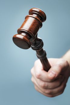 Man holding a wooden mahogany gavel in his hand. Short depth-of-field.