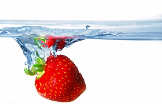 Fresh juicy strawberry in the blue water with splash