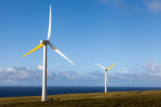 Two wind generators produce renewable energy overlooking Pacific Ocean