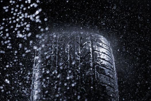 Car tire in rainy conditions. Very short depth-of-field.