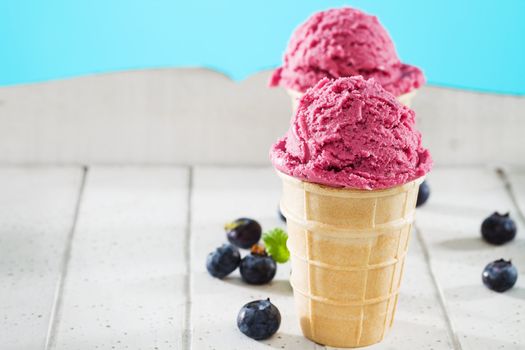 blueberry ice cream in front of other on white wood