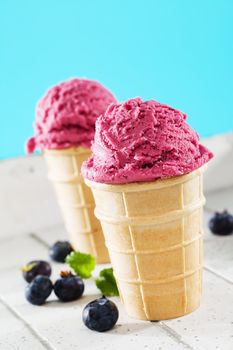 two blueberry ice cream waffles on white wood with blue background