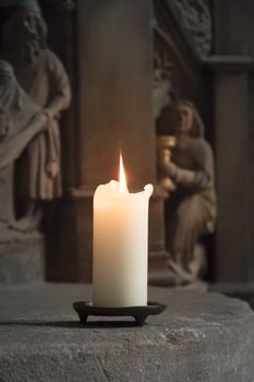 An image of one burning candle in a church