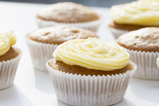 Fresh cupcakes some with with yellow frosting, some unfrosted.