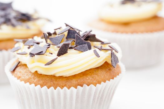 Vanilla cupcake with yellow frosting and chocolate flakes.