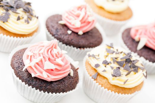 Chocolate and vanilla cupcakes frosted and topped with chocolate flakes.