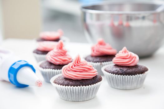 Chocolate cupcakes just decorated with pink frosting