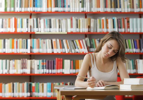 Portrait of a serious young student reading a book in a library