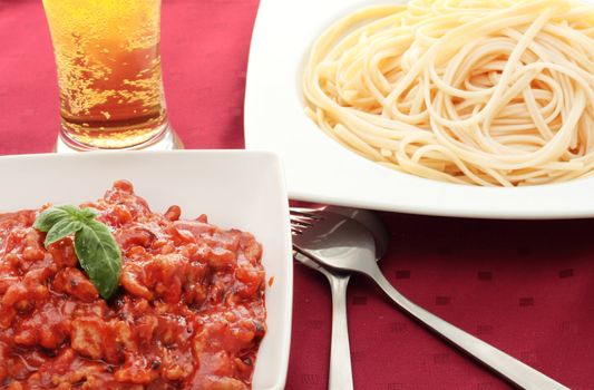 pasta dish with minced meat with tomatoes and beer with knife and fork