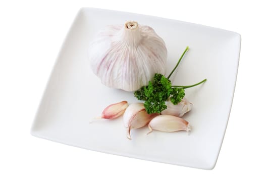 dish of garlic with teeth and head of garlic with parsley cut off and isolated