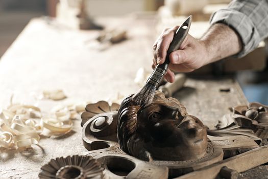 Close Up of carpenter apply varnish to a wooden sculpture