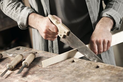 Carpenter saws plank by handsaw