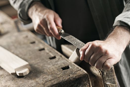 Carpenter working on a piece of wood with a file