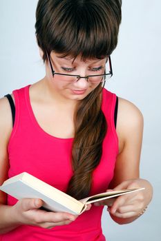 Teen girl in glasses reads the book carefully