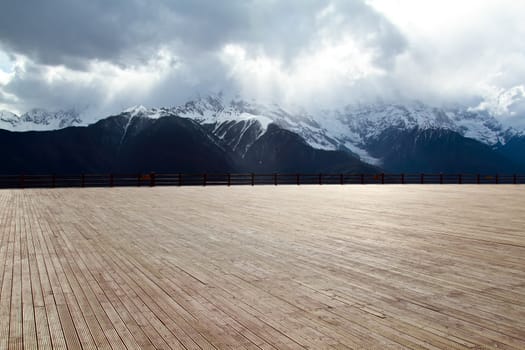 Wood floor with a background of mountains and clouds