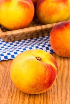 Fresh peaches in the basket on a wooden table.