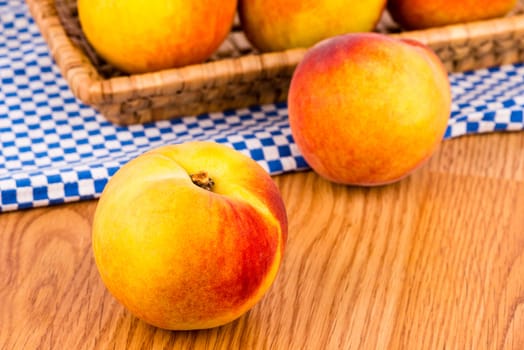Fresh peaches in the basket on a wooden table.