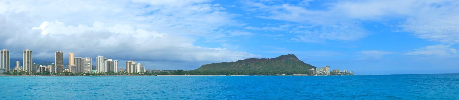 A panoramic shot of Diamond Head and Waikiki Beach with the towering buildings of Honolulu towering in the background