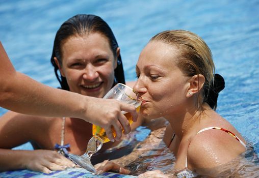 Two girls drink beer in pool