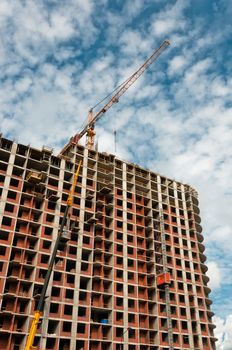 Crane developing new building with beautiful cloudscape on background