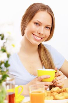 Beautiful young woman drinking tea from yellow cup