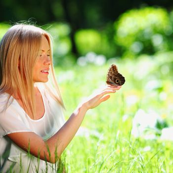 Woman playing with a butterfly on green grass