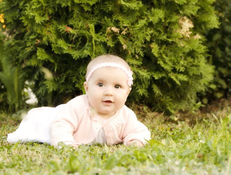 Happy baby girl in the grass looking at camera