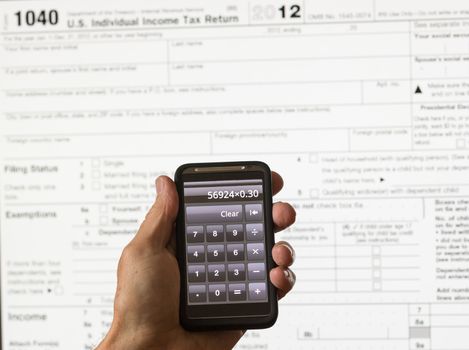 Electronic tax form 1040 for 2012 for US individual return on screen with smartphone calculator