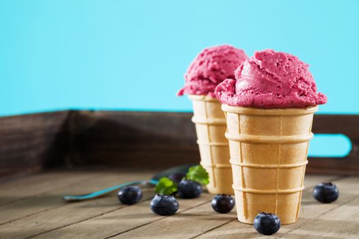 blueberry ice cream in waffles on wood with blue background