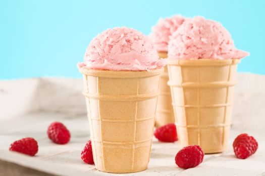 raspberry ice cream in a waffle on white wood and blue background