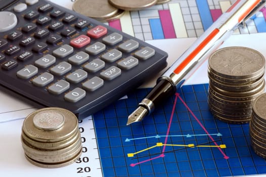 calculator, pen and cooins on sheet of financial data