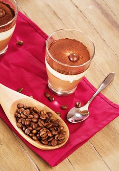 tiramisu dessert on wooden background with coffee beans in a wooden spoon