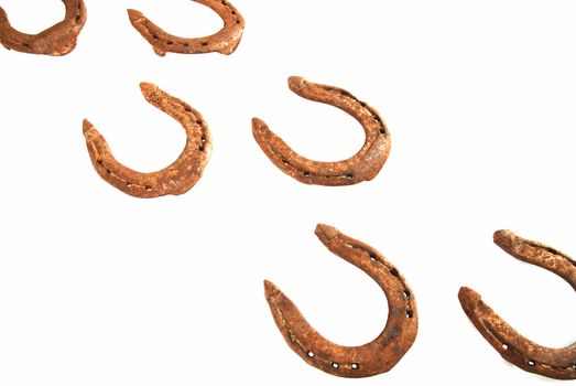 Two rows of old rusty horseshoes on white