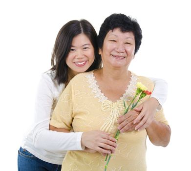 Daughter giving carnation flowers to her mother over white background