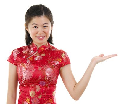 Chinese Asian woman in Traditional Cheongsam showing empty hand over white background.