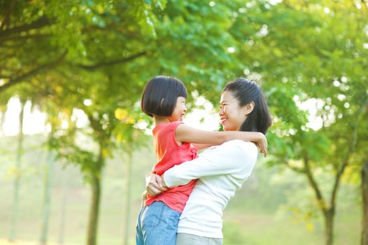 Asian mother hugging her daughter at outdoor park