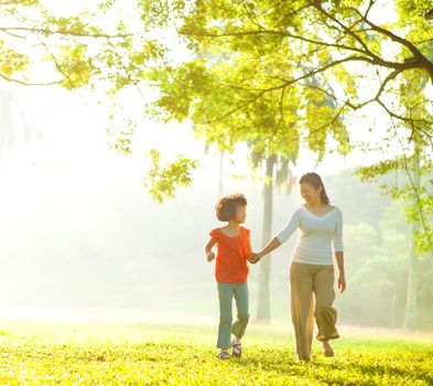 Asian mother and daughter holding hands walking at outdoor park