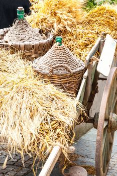 Autumn wooden cart harvest and demijohn wicker with bales of hay