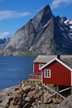 Traditional red fishing rorbu hut on the coast of fjord on lofoten islands in Norway