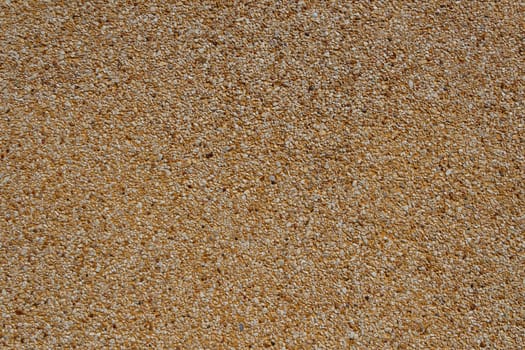 Tiny gravel texture on brown concrete wall in sunny day