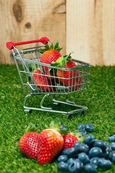 Strawberries in a shopping cart in front of a timber wall