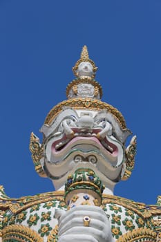 White guardian statue at the Temple of Dawn was beautifully decorated with tiny pieces of colored ceramics and Chinese porcelain placed delicately into intricate patterns. It is one of Bangkok's world-famous landmarks.