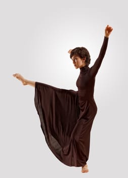 Girl dancing in a dark dress with a gray background. isolate
