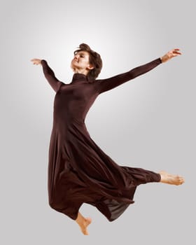 Girl dancing in a dark dress with a gray background. isolate