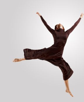 Girl dancing in a dark dress with a gray background. isolate