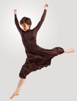 Girl dancing in a dark dress with a gray background. isolate
