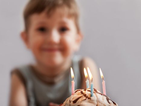 Little smiling child boy blowing birthday celebration sweet cake candle fire