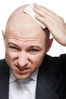 Tired or upset businessman wiping or drying bald sweat head with handkerchief or tissue